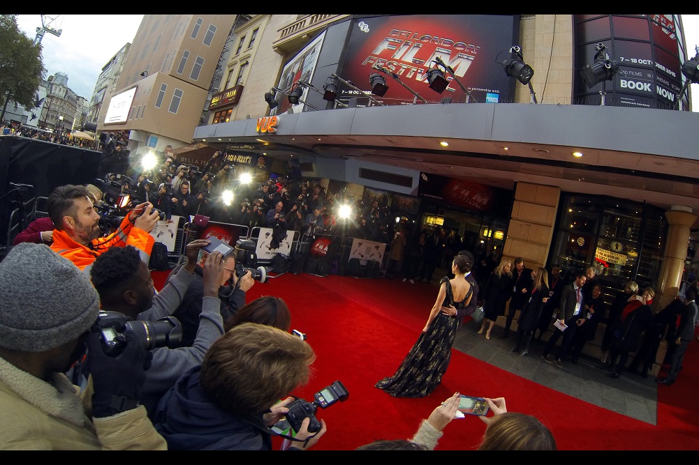 Four flashes discharge as Colin Farrell and Rachel Weisz pose for the Paps. But the light coming from the guy in the orange jumpsuit on the right is even more intense.