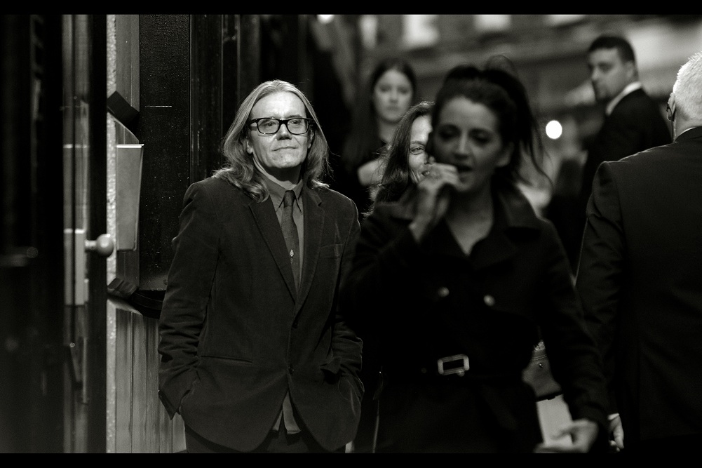 Lady in foreground : "He's the producer, I think? Anyway, let him in. His hair is AMAZING"
