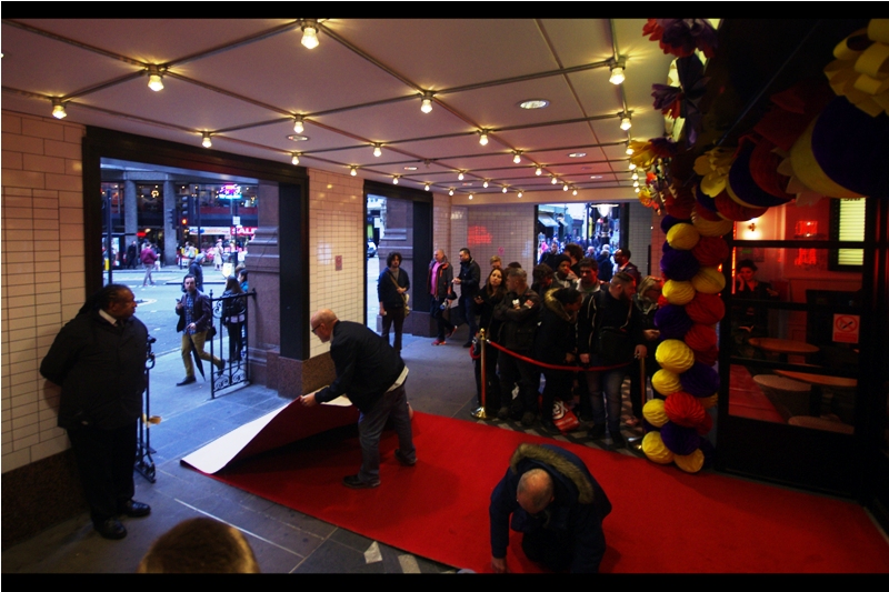 T-minus 1hr, and we have a red carpet. However, it doesn't look like the kind of red carpet that (say) Keanu Reeves (who is in this movie) would fly all the way from (say) Los Angeles to walk upon. No matter how good those Triceratops Ribs being hawked by the neon sign in the background might be.