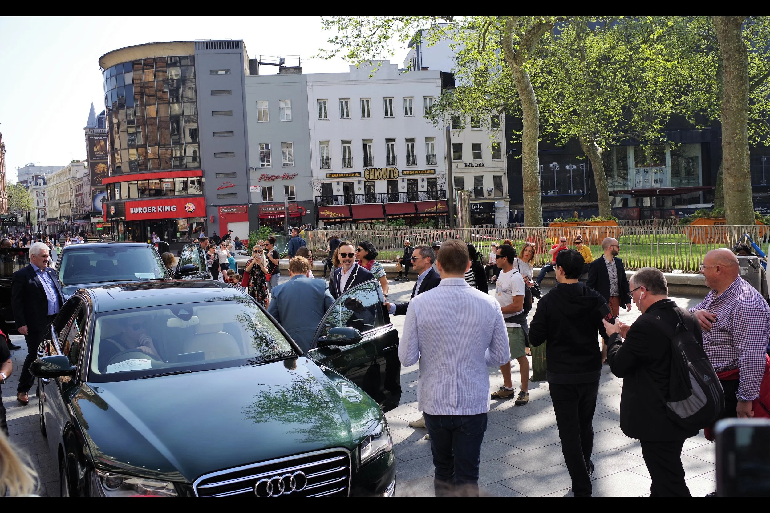 Not one but two cars pull up, and the front one dispenses two of the film's producers : David Furnish (pictured, white trimmed jacket), whose husband is singer Elton John, one of the OTHER producers of this film.