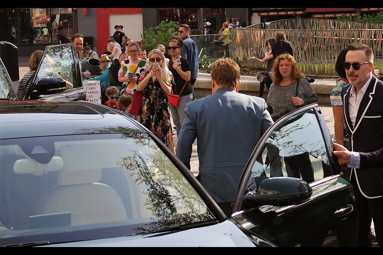 The woman with the iPhone gets The Shot that neither the Paparazzi (on the rear/other side of the car) nor I (front of car and hurriedly shifting right) do. Photography is about timing and opportunity ..... more so than equipment sometimes!