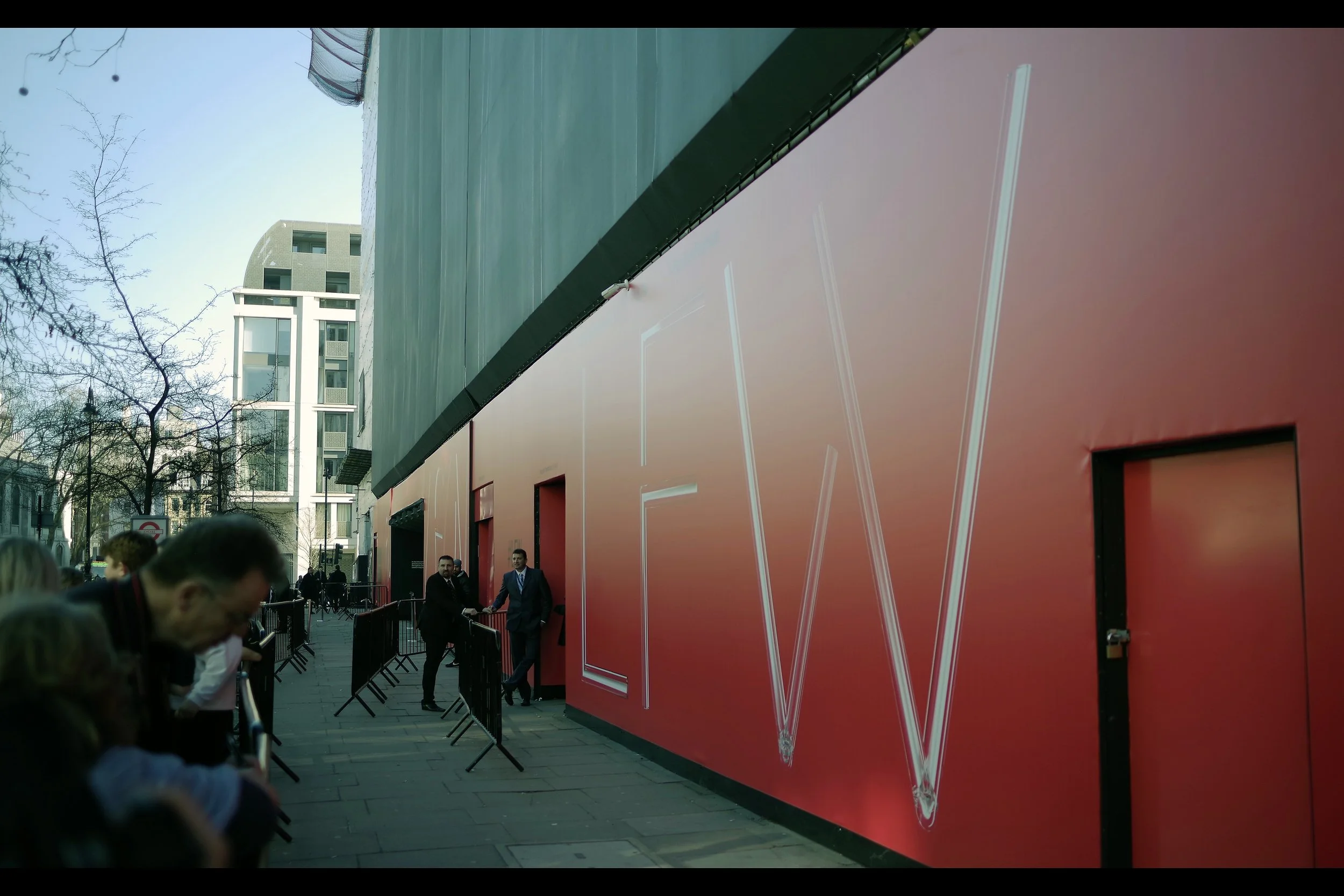 “Yeah, some lout just came along and used his car keys to scratch our nice red wall. Frankly, I think it’s a miracle that if you look at the marks a certain way they appear to spell out the letters of London Fashion Week.. but that’s just a lucky coincidence….”