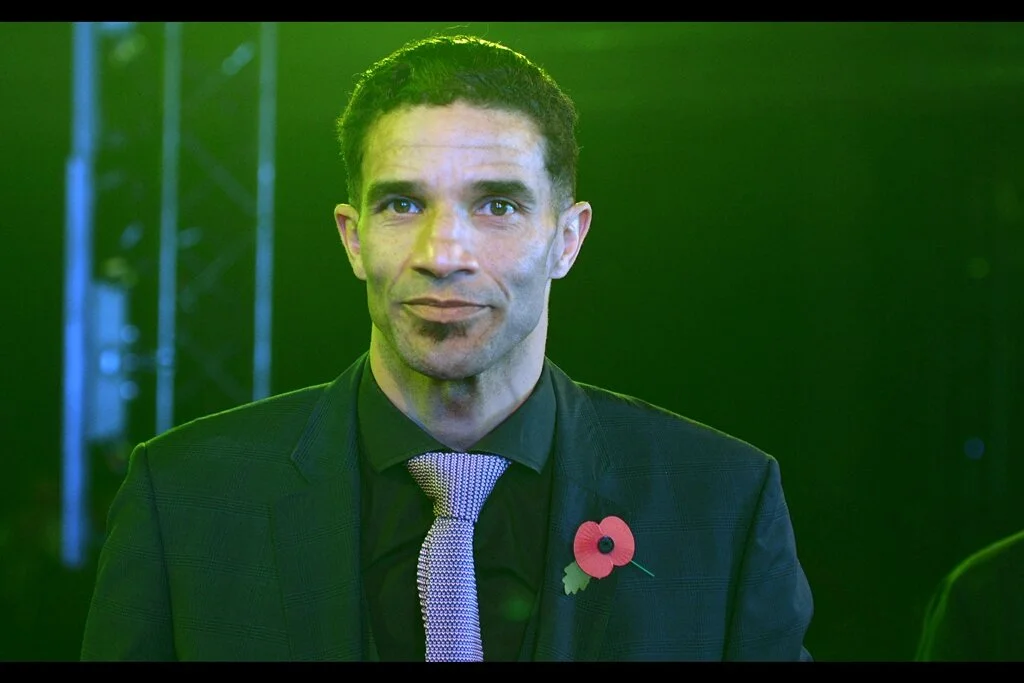 David James’ expression is something along the lines of “I know you’re going to compliment my tie pattern as cover for the fact that you’re going to be taking more photos of my girlfriend than you are of me” . And….. erm….