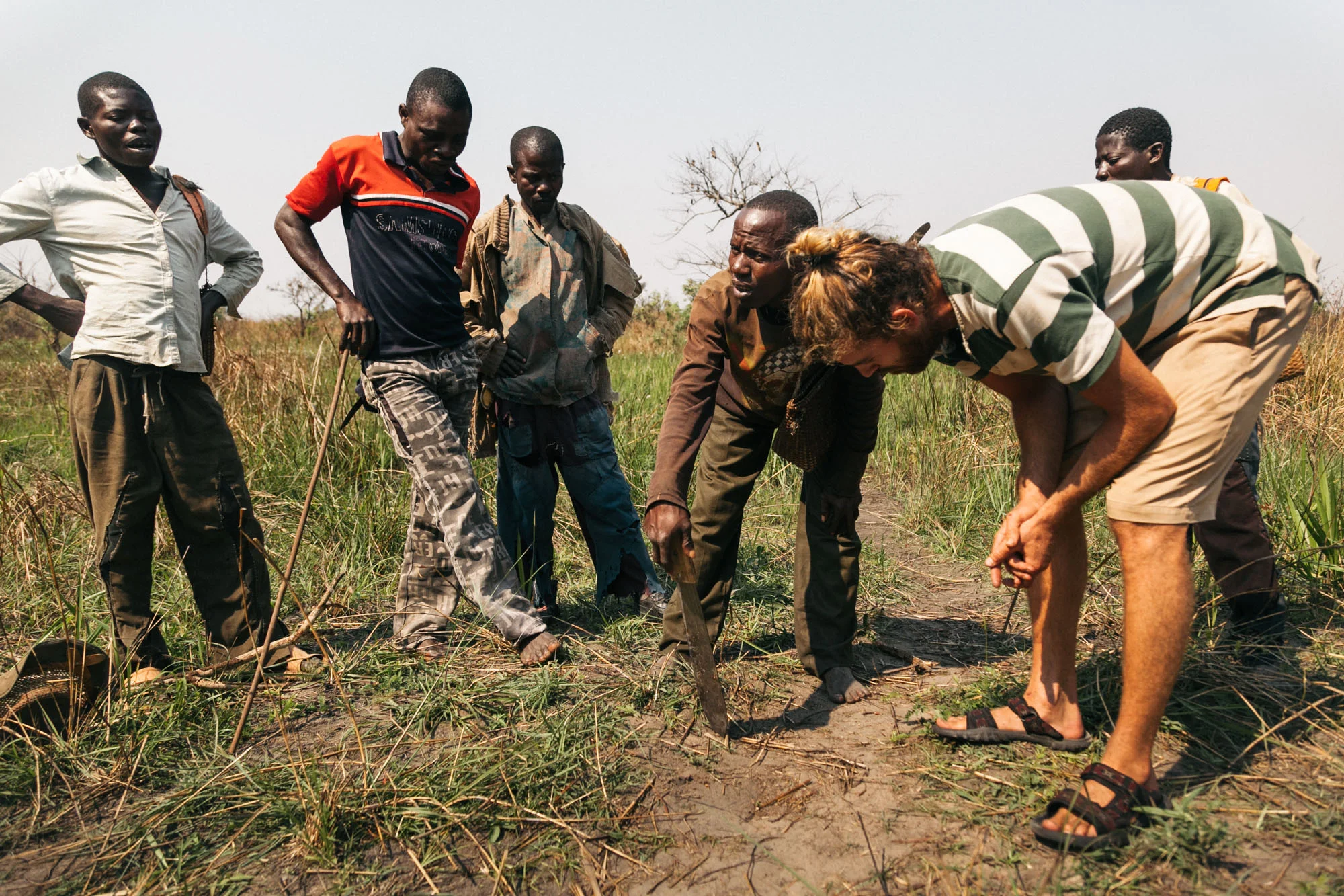 A fisherman draws in the dirt with a machete to outline the best route for tackling the next set of rapids.