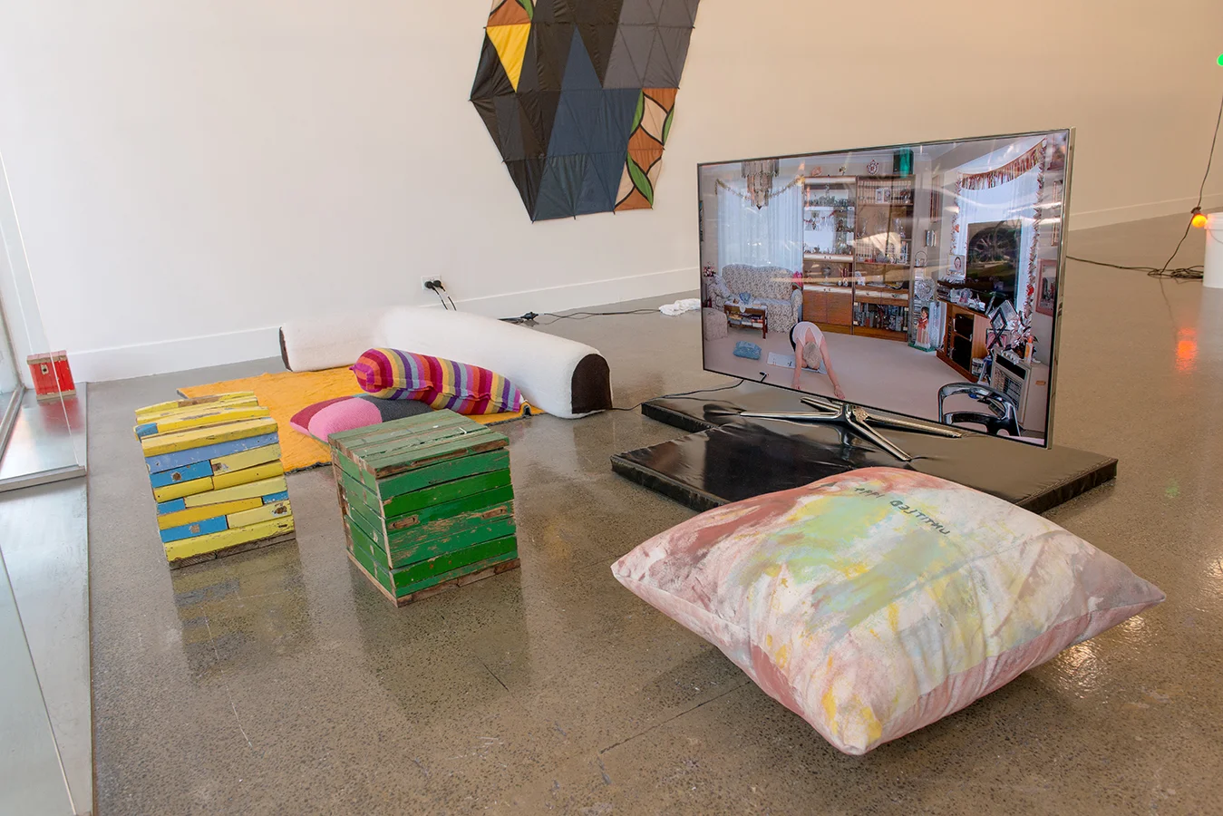 (front) Katherine Hattam , Specific Object (Green, Yellow, Red), wood. Courtesy the artist and Daine Singer. Elizabeth Newman , Soft Furnishings (various) , 2008-2009, Fabric, cushions, tree trunks, vinyl cushion. Courtesy the artist and Neon Park. Natasha Madden, Be My Love (Macbook Duet) , 2014, Digital Film on USB, TV, Nanna's Fabric. Courtesy the artist. Lucina Lane (background) Alek O. , Untitled (Umbrellas) , 2015, Polyester Fabric from Umbrellas. Courtesy the artist and Frutta Gallery, Rome.