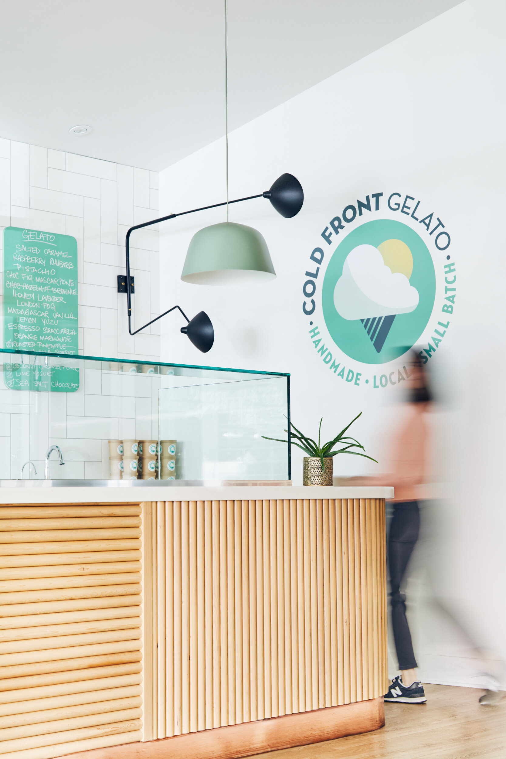  A woman walks behind the counter at Cold Front Gelato in Naniamo, British Columbia, Canada. Interior design by Alana Dick of Ivory Design Company. 