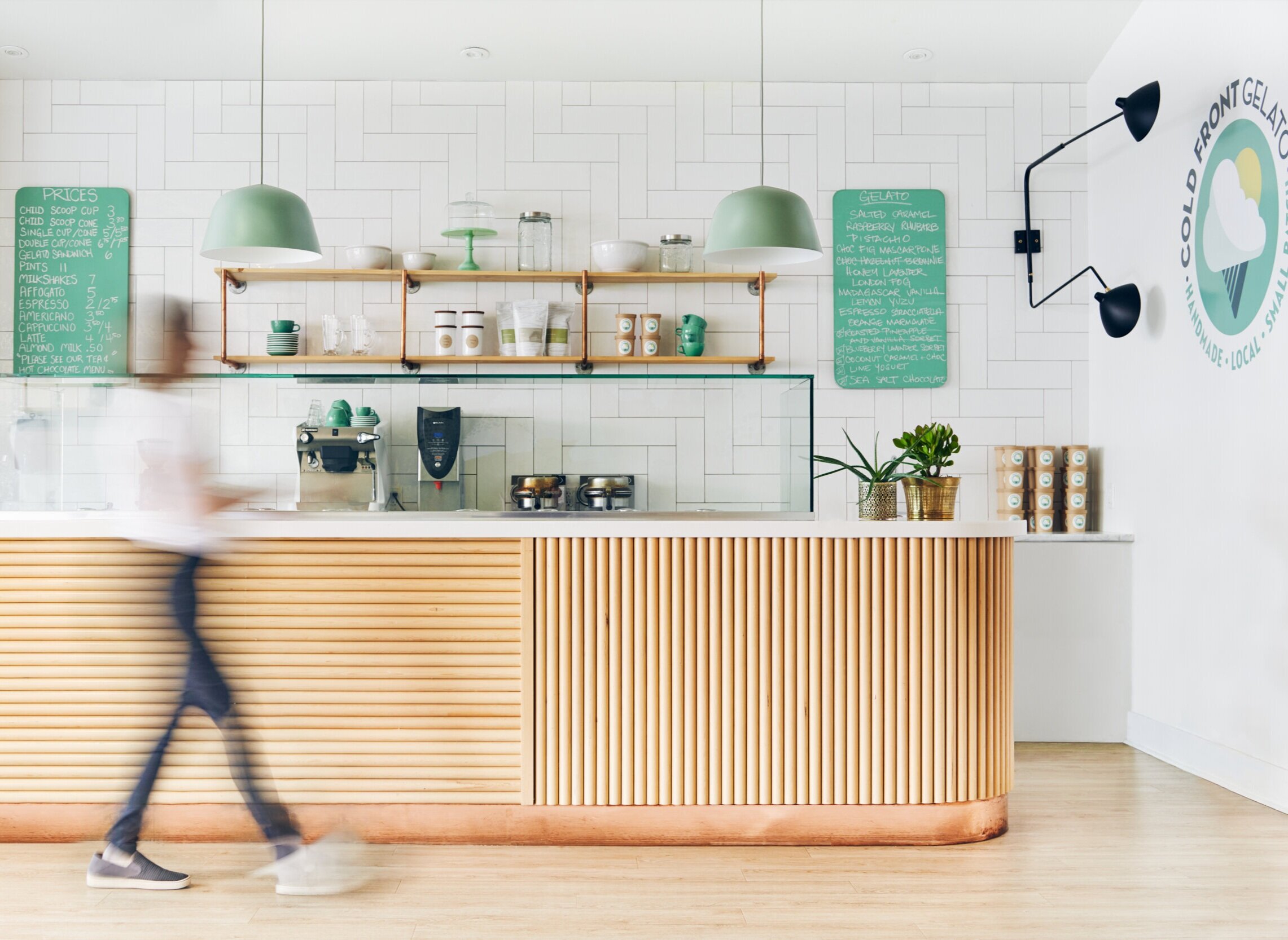  A woman walks in front of the counter in Cold Front Gelato in Naniamo, British Columbia, Canada. Interior design by Alana Dick of Ivory Design Company. 