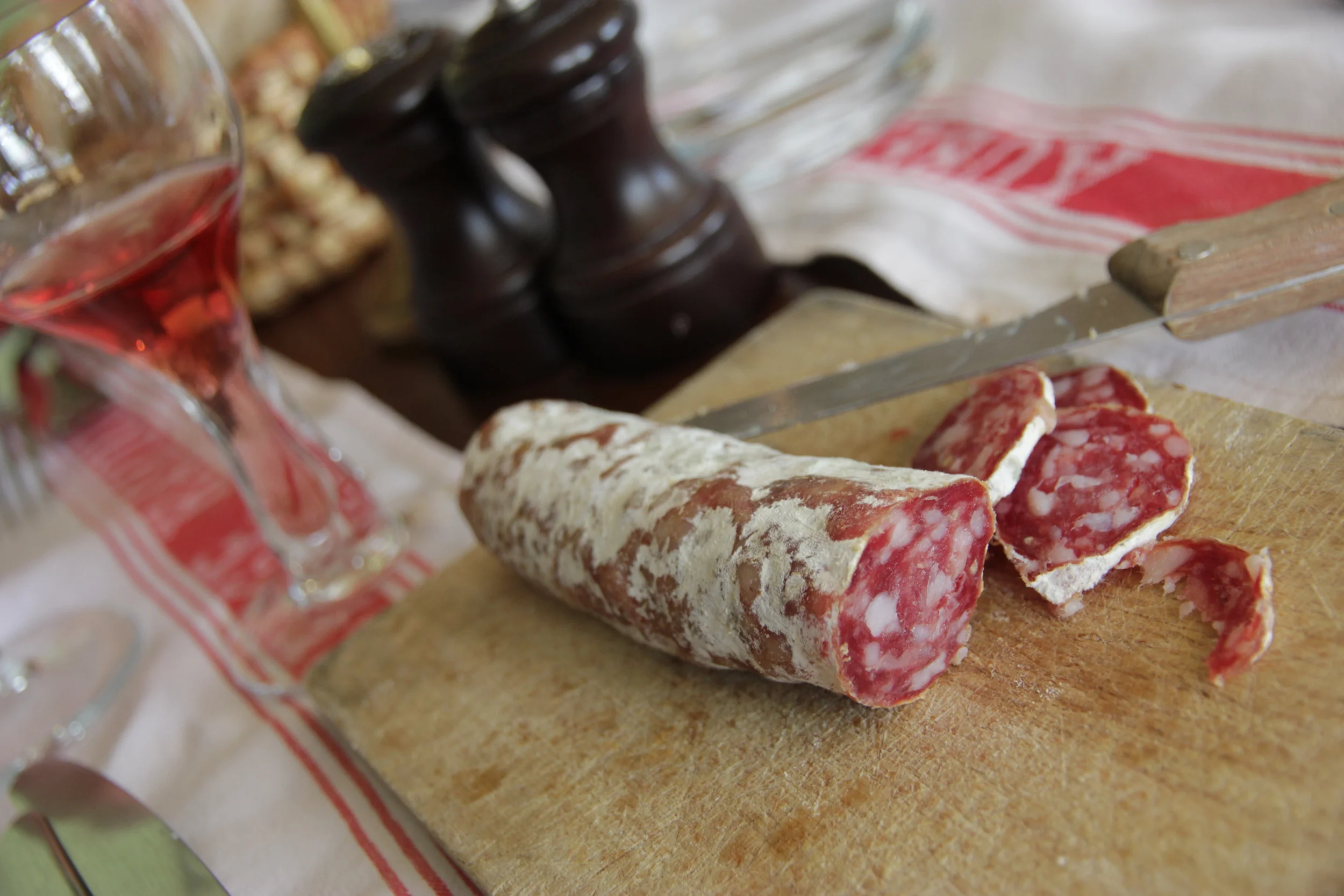 Dry sausage flecked with bits of delicious fat. The sparkling rosé wine in its vintage glass is in the background.
