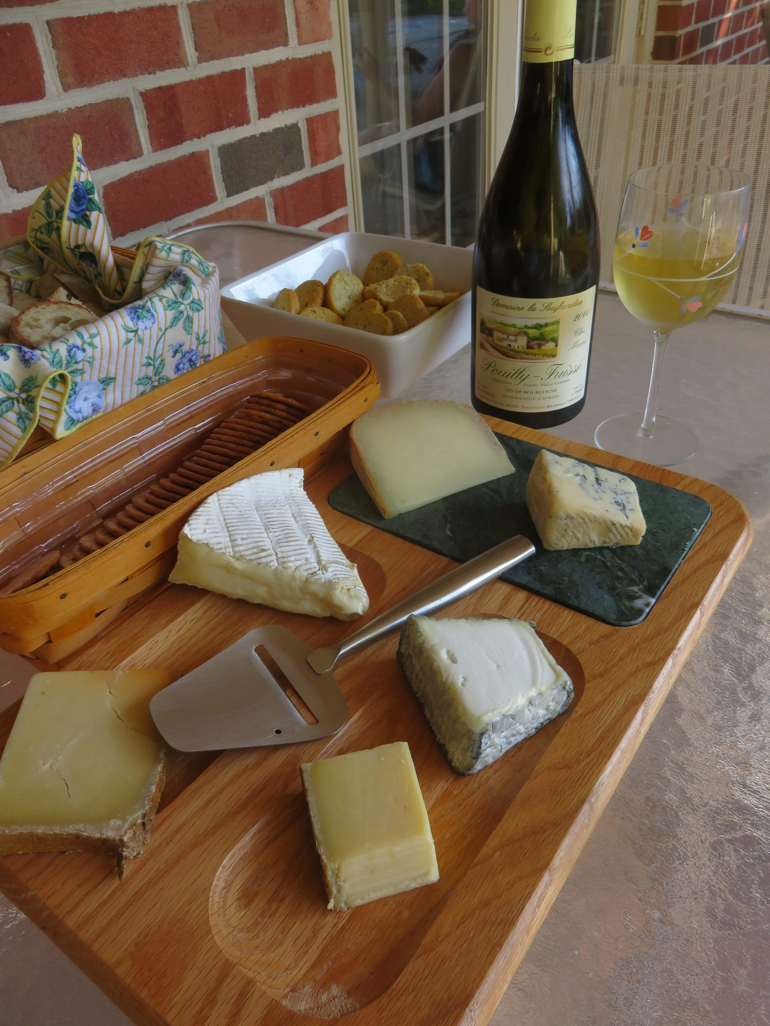 Starting from closest to the wine bottle and moving clockwise: Ossau-Iraty, Bay Blue, Valençay, Comté, Beaufort, Brie