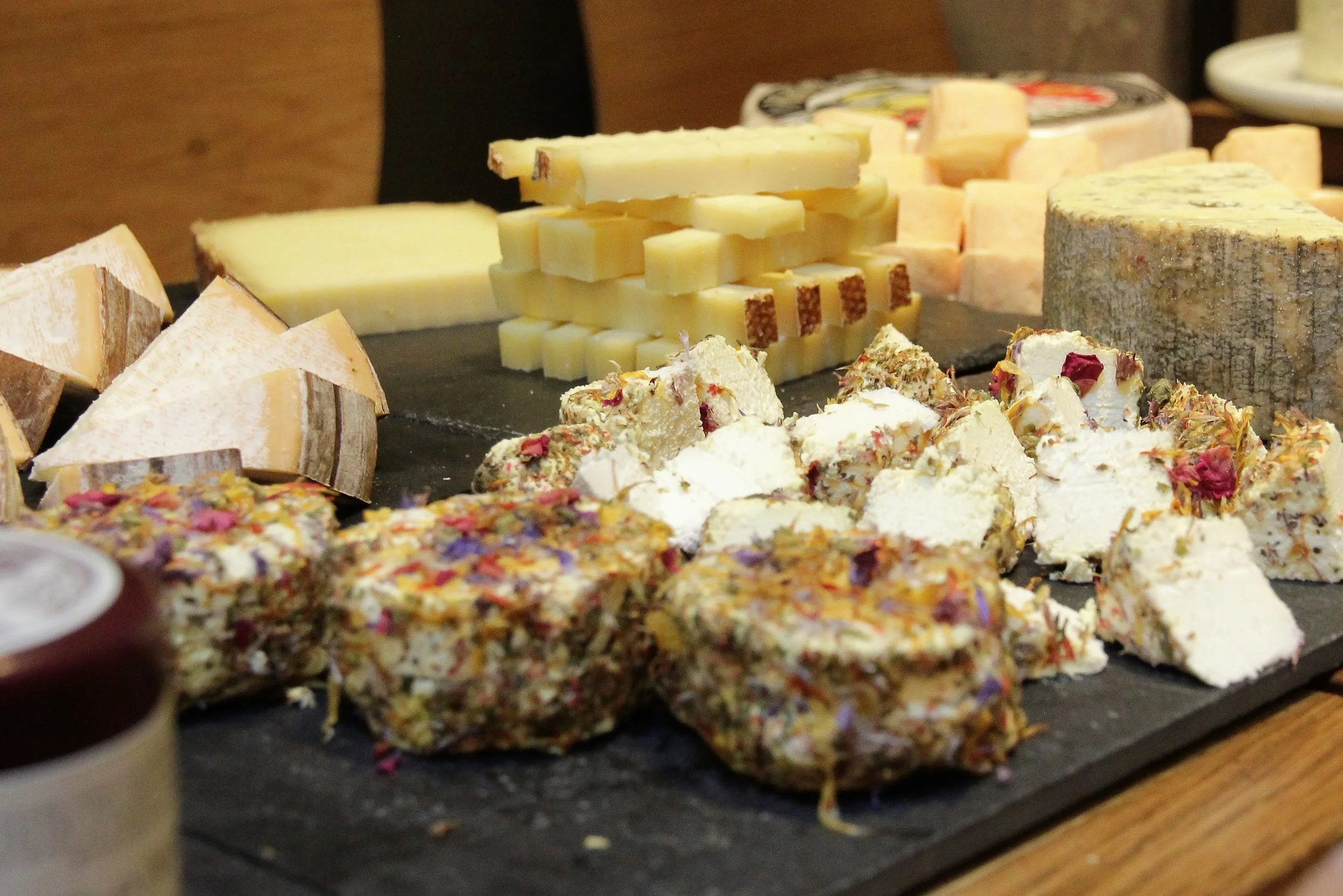 Un fromage de chèvre incrusté de pétales de fleurs. Un peu bizarre, mais pas mal quand même. Du gruyère derrière.