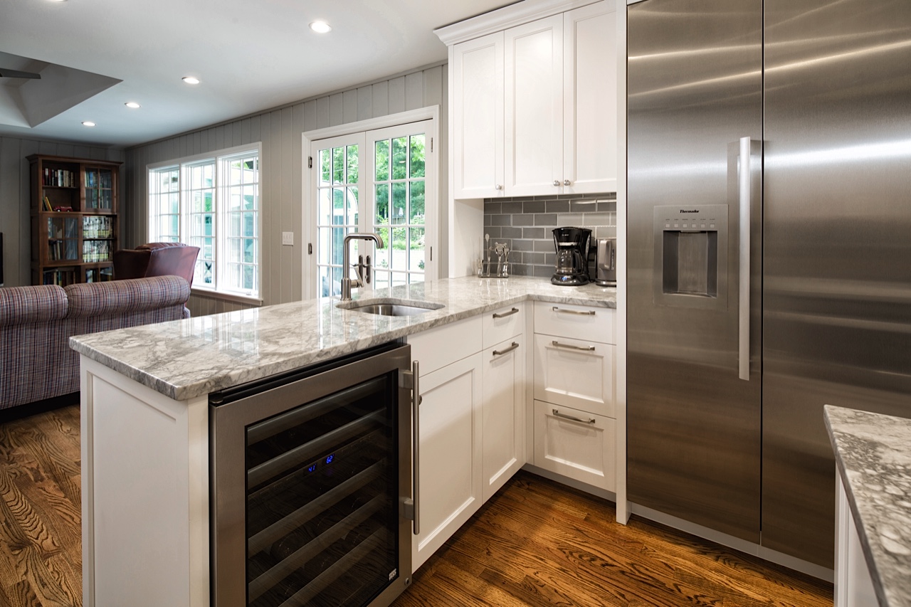 Open Space: By removing the wall to the living room, sight lines and conversation flow freely throughout the home. A beverage cooler and auxiliary sink are perfect for entertaining and preparing larger meals. Divided lite windows, added French doors, and wood paneling retain the home’s classic character while blending with the modern composition of the kitchen remodel.