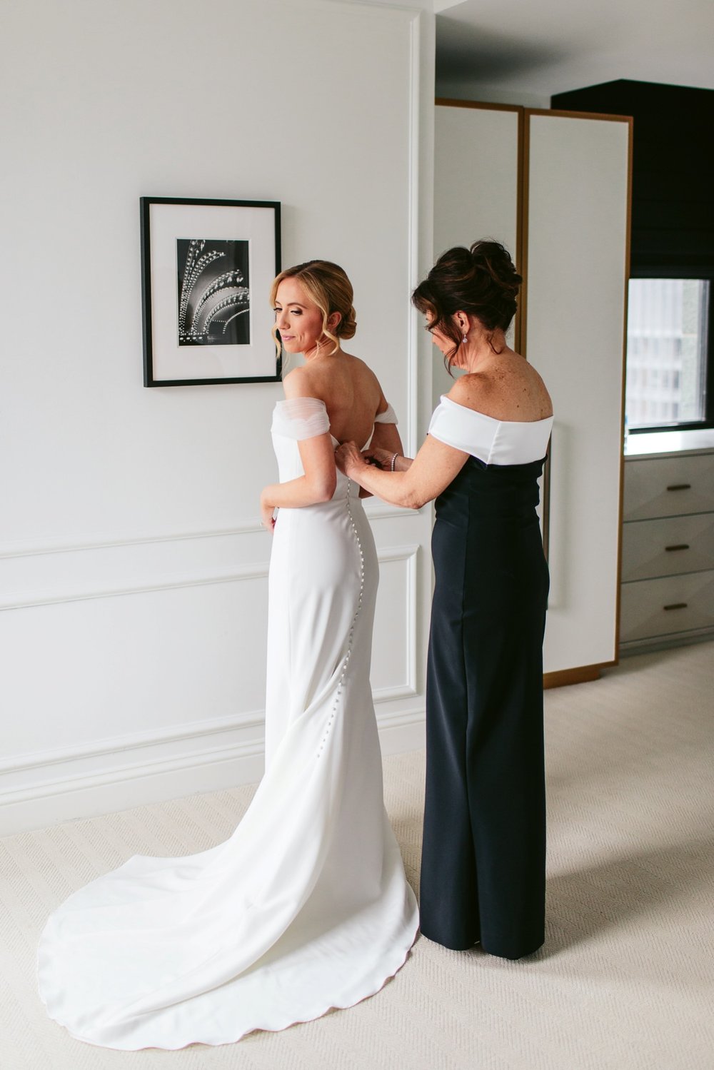 mom helping put on wedding dress