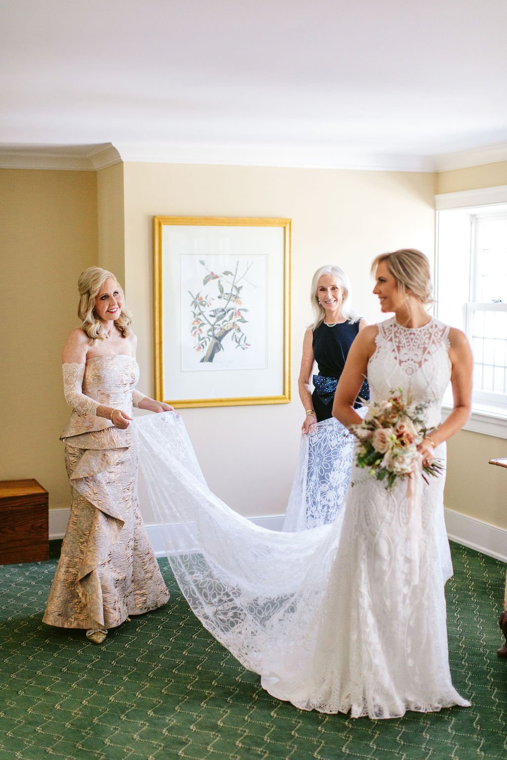 Mother helping with bride's train in getting ready suite