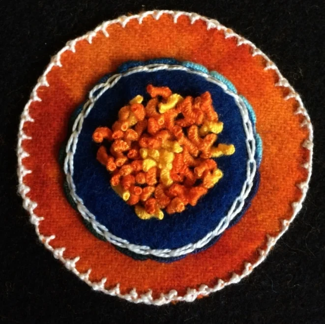 The Palestrina Stitch is done in white around the edge of the circle.