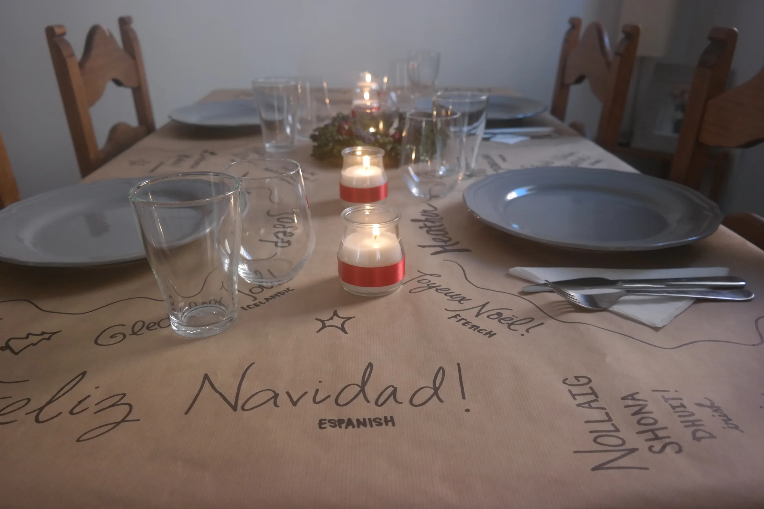 Our Christmas dinner table. Covering our table in brown paper and writing "Merry Christmas" in different languages is a very cheap way to decorate and a super easy way to clean up quickly!