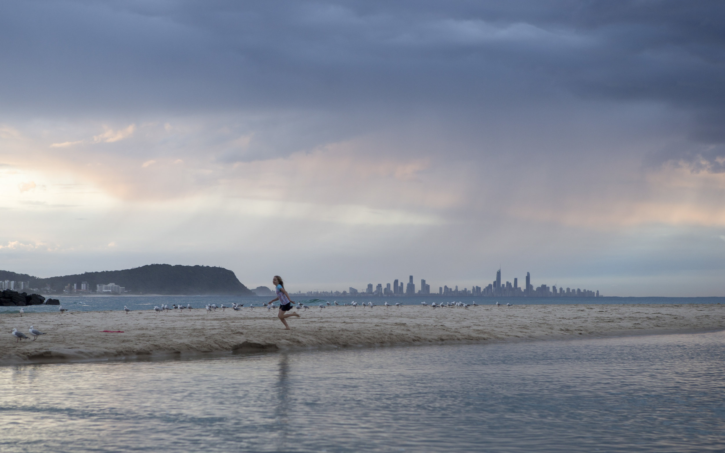  A young girl running along the beach at Currumbin Alley, not a care in the world as a storm approaches, Gold Coast, Qld, Australia 