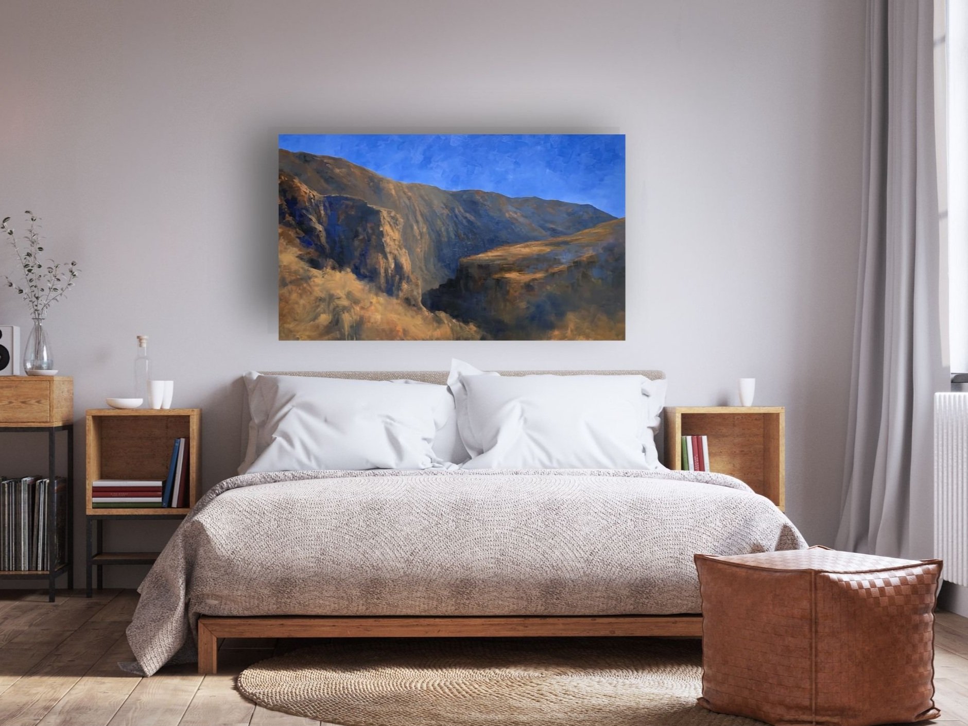 Neutral bedroom with king bed and desert landscape on the wall of mountains and cobalt blue sky