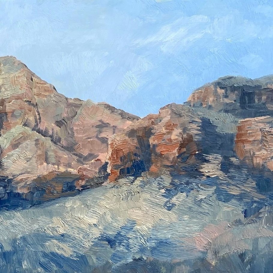 Plein air landscape painting of greening of the desert mountains using square brushes and pale blue sky