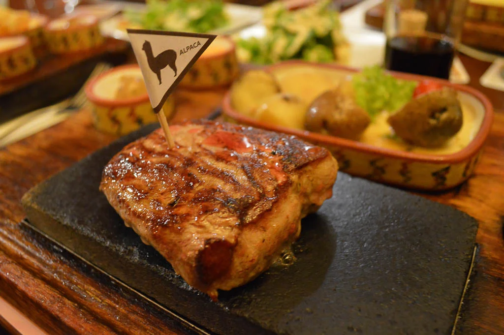 An alpaca steak with a triangular sign on it with an alpaca silhouette at the Zig Zag restaurant in Arequipa Peru