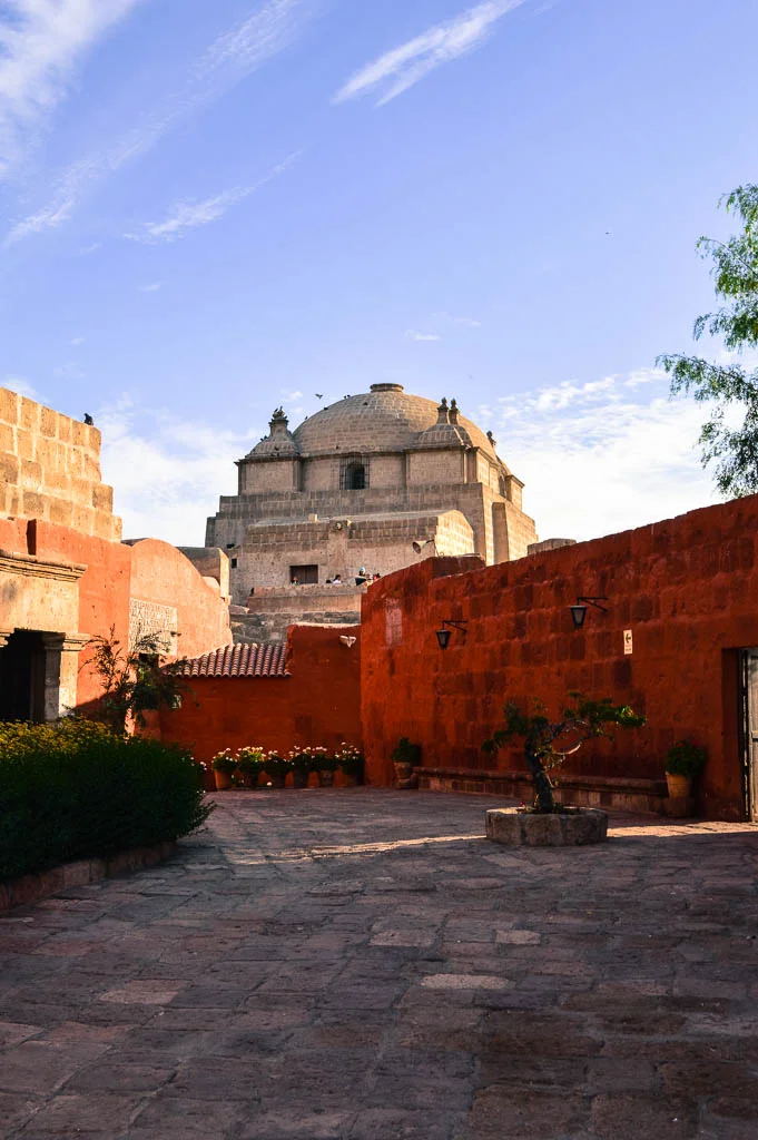 A view of the Monasterio de Santa Catalina in Arequipa Peru. It is a courtyard with red walls.