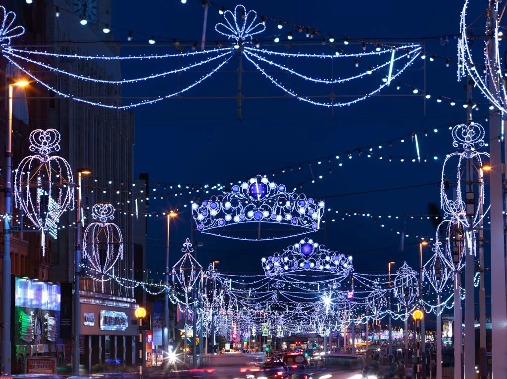 Blackpool Illuminations lit up at night, with crown and tiaras lit up across the road.
