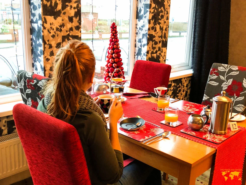 A redheaded women drinking coffee at breakfast at the Number One South Beach hotel in Blackpool at Christmas time.