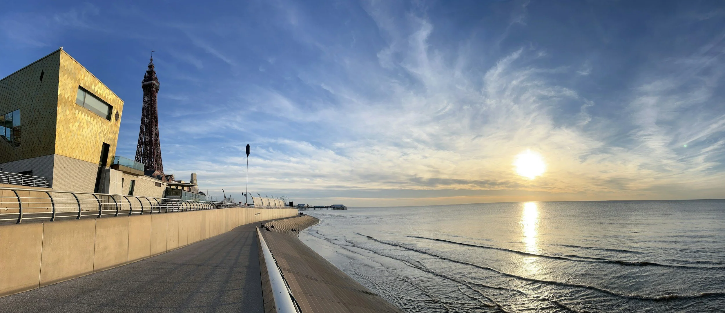 The Blackpool tower from the beach steps with the tide coming in at sunrise on a clear day.