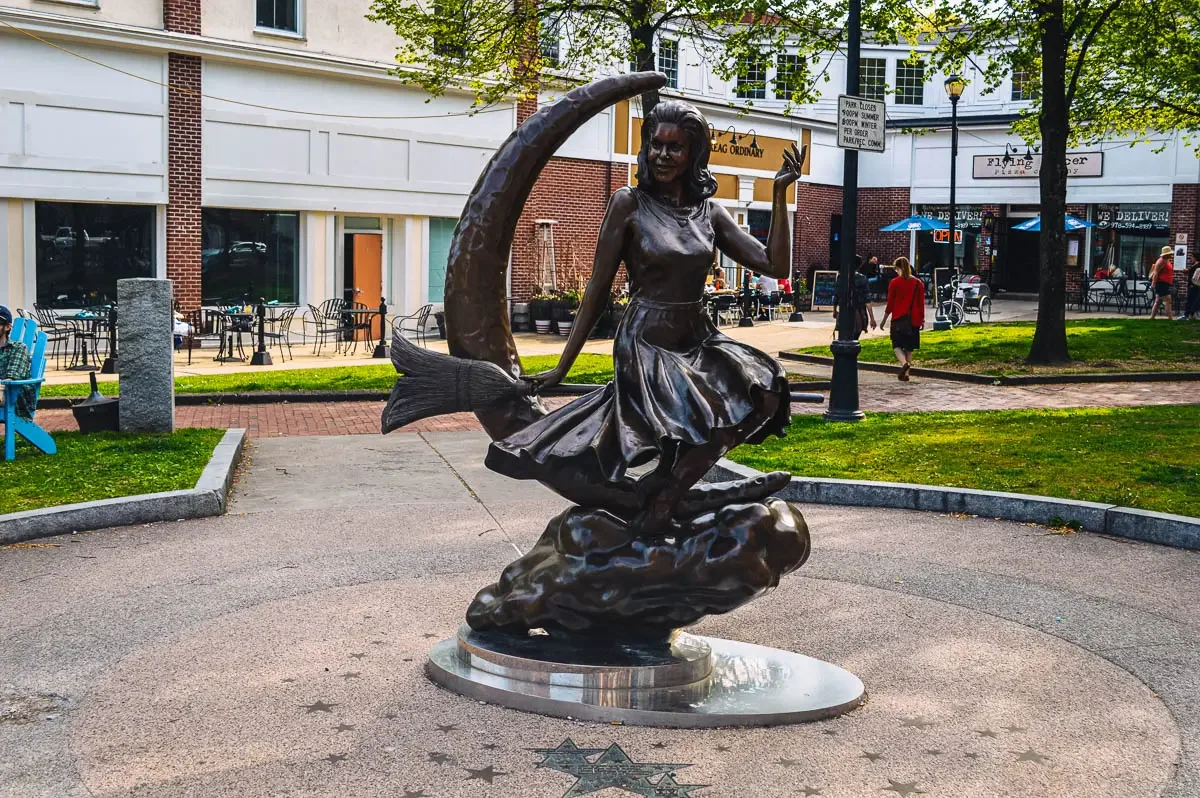 Bronze statue of a witch sitting on a broomstick in front of a moon. The bewitched sculpture or samantha statue in salem Massachusetts.