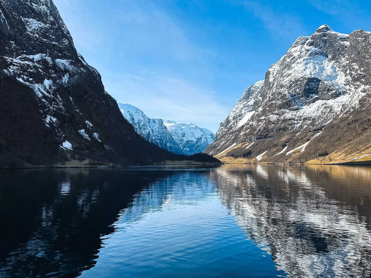 Naeroyfjord fjord cruise with snow capped mountains reflected in water Norway