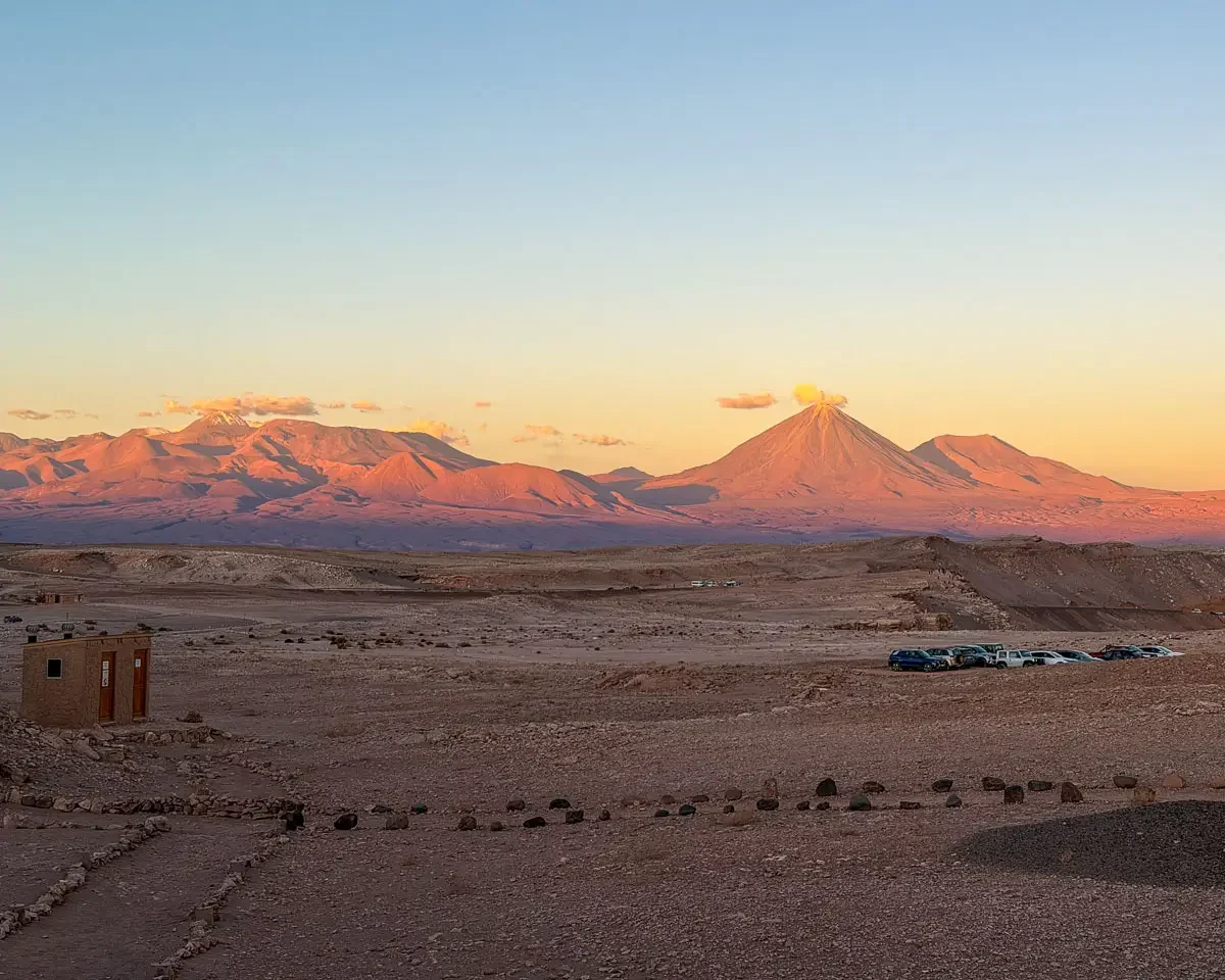 view of volcanos and mountains sunlit at golden hour with pinks and purples in valle de la luna in atacama desert chile