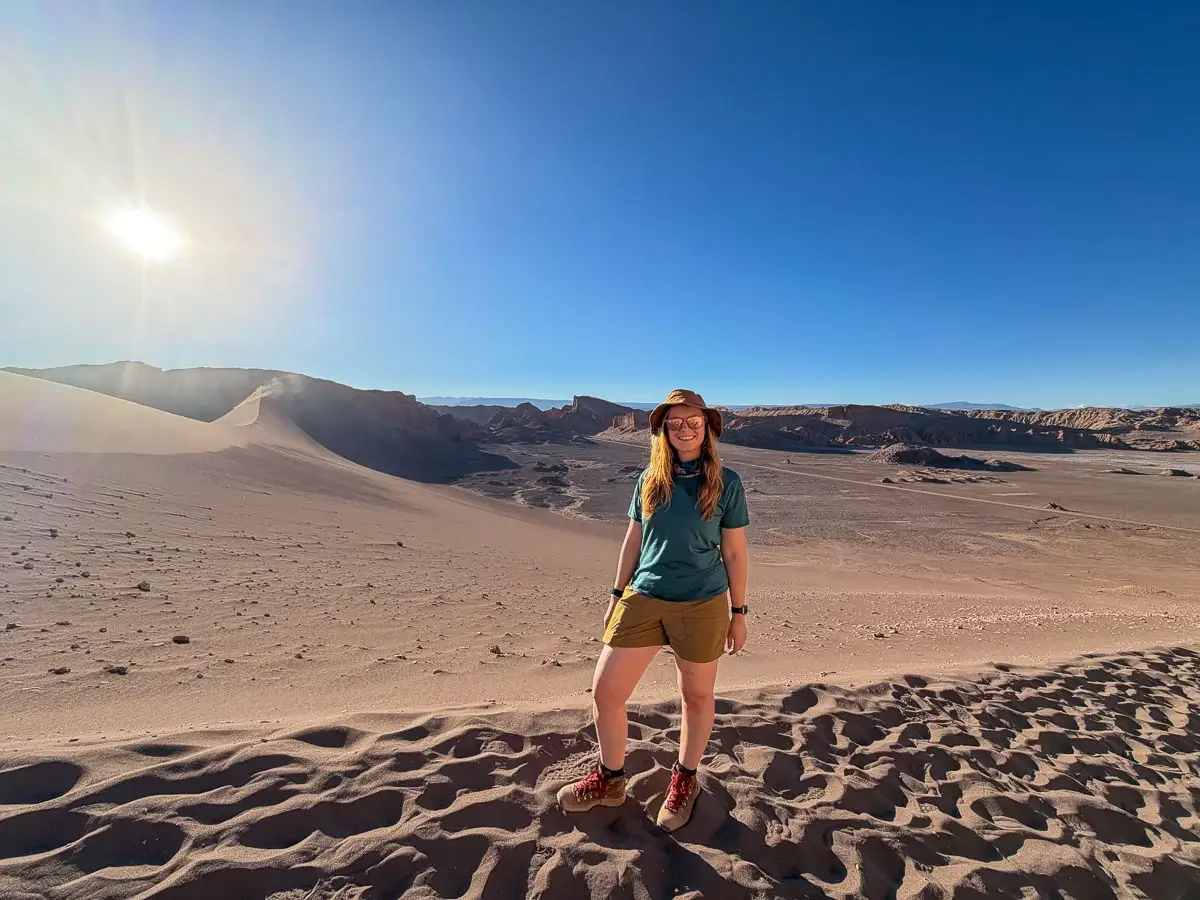 Ginger girl in hiking gear posing in front of the duna major at valle de la luna in the atacama desrt in chile.