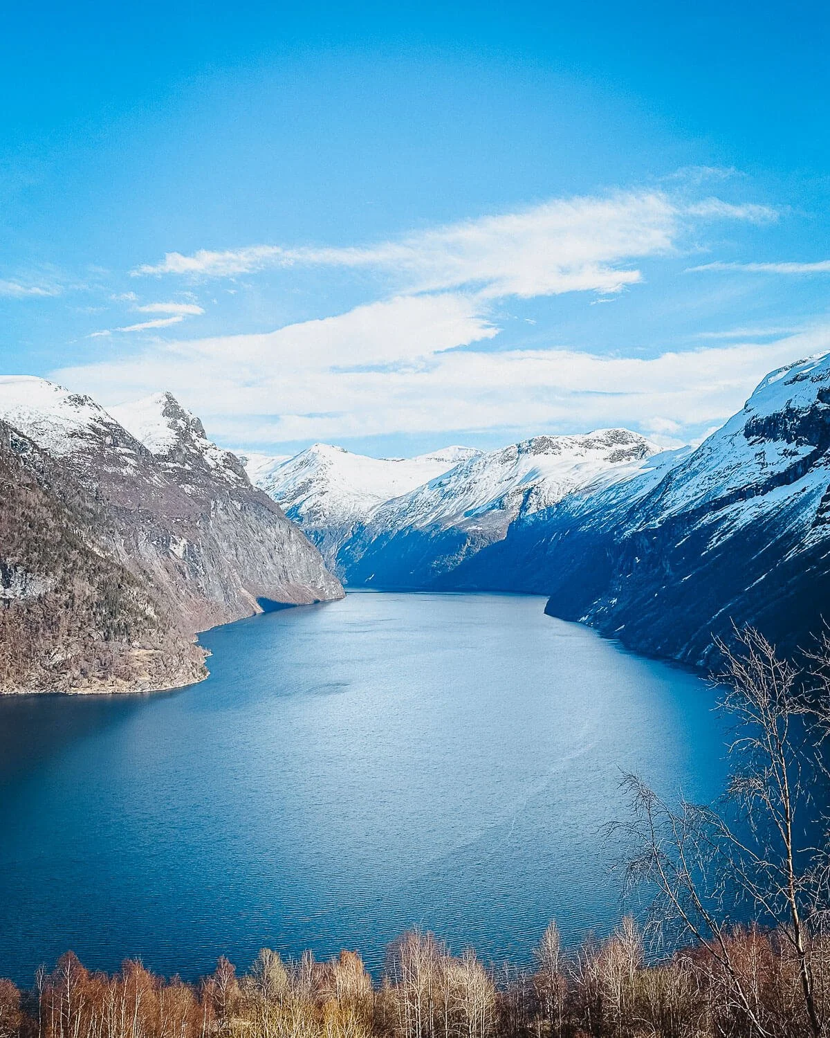 Panoramic view down the Geirangerfjord surrounded by snow covered mountains Norway