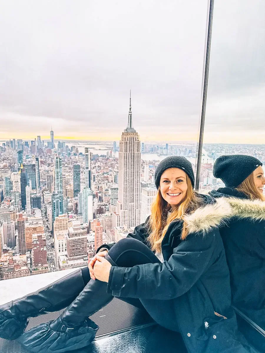 ginger woman sitting on the ground at the top of the summit one vanderbilt building overlooking the empire state building