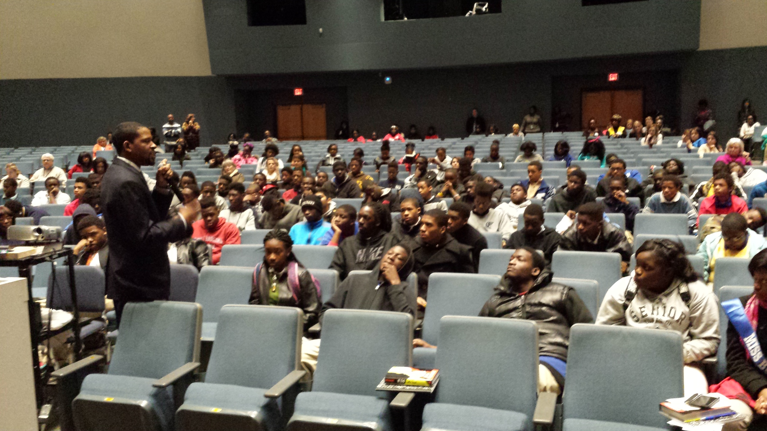 Burke High School Principal, Maurice Cannon, speaking to students as they return from their various workshops. Providing encouraging words regarding the value of what they learned until all students arrive in the auditorium.