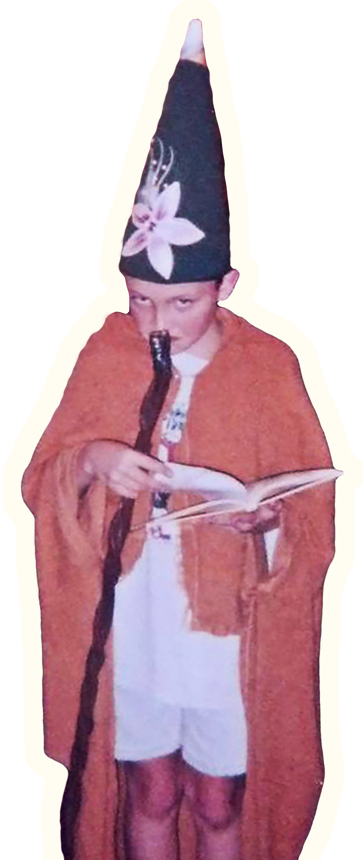 Child dressed as a wizard with a tall, pointed hat decorated with a large flower, holding a magic wand and a book.