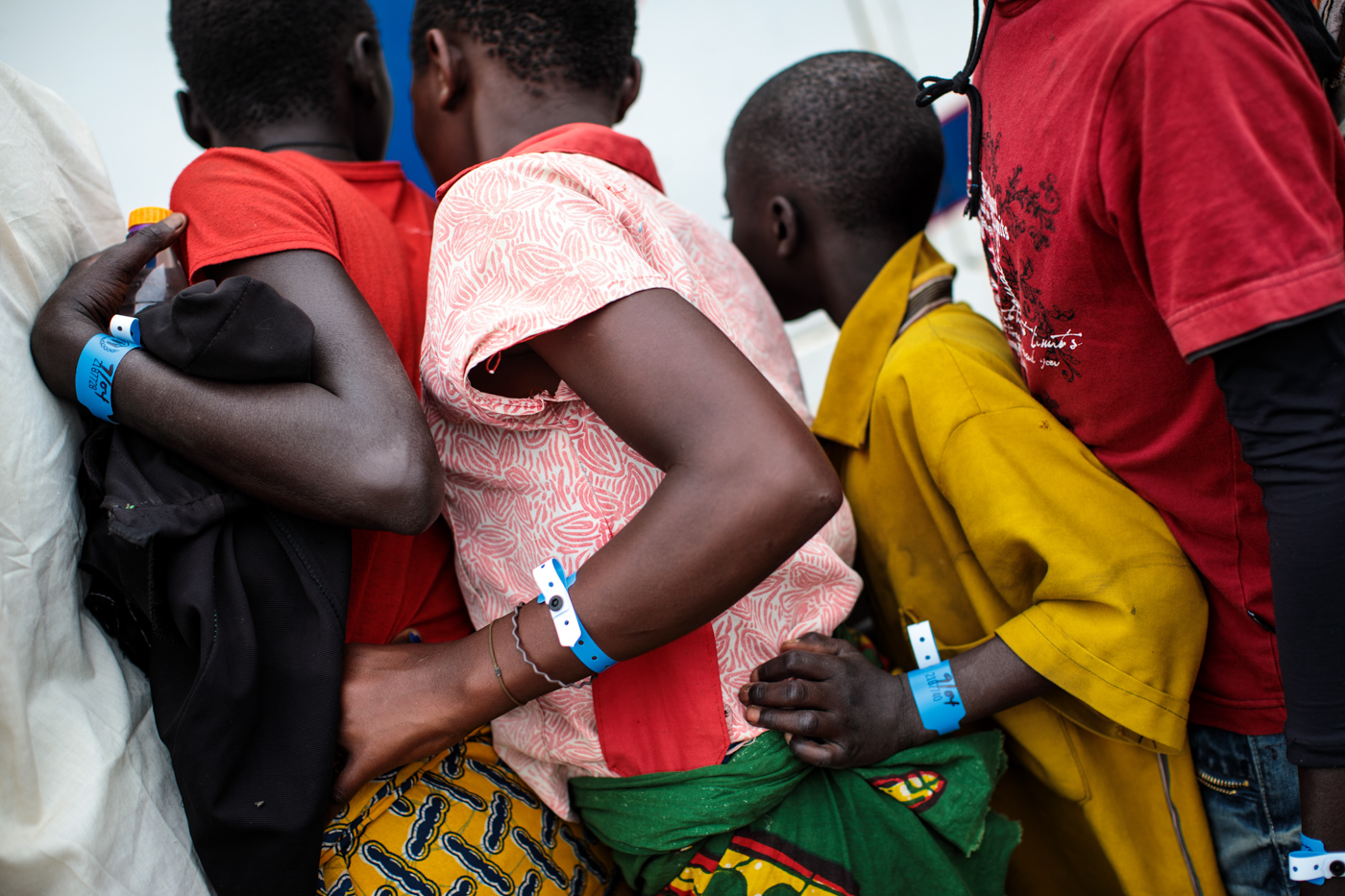  NSONGA, UGANDA: Refugees from the Democratic Republic of Congo, wearing registration wristbands, prepare to board a bus from the Nsonga landing site to a reception centre on April 9, 2018. 