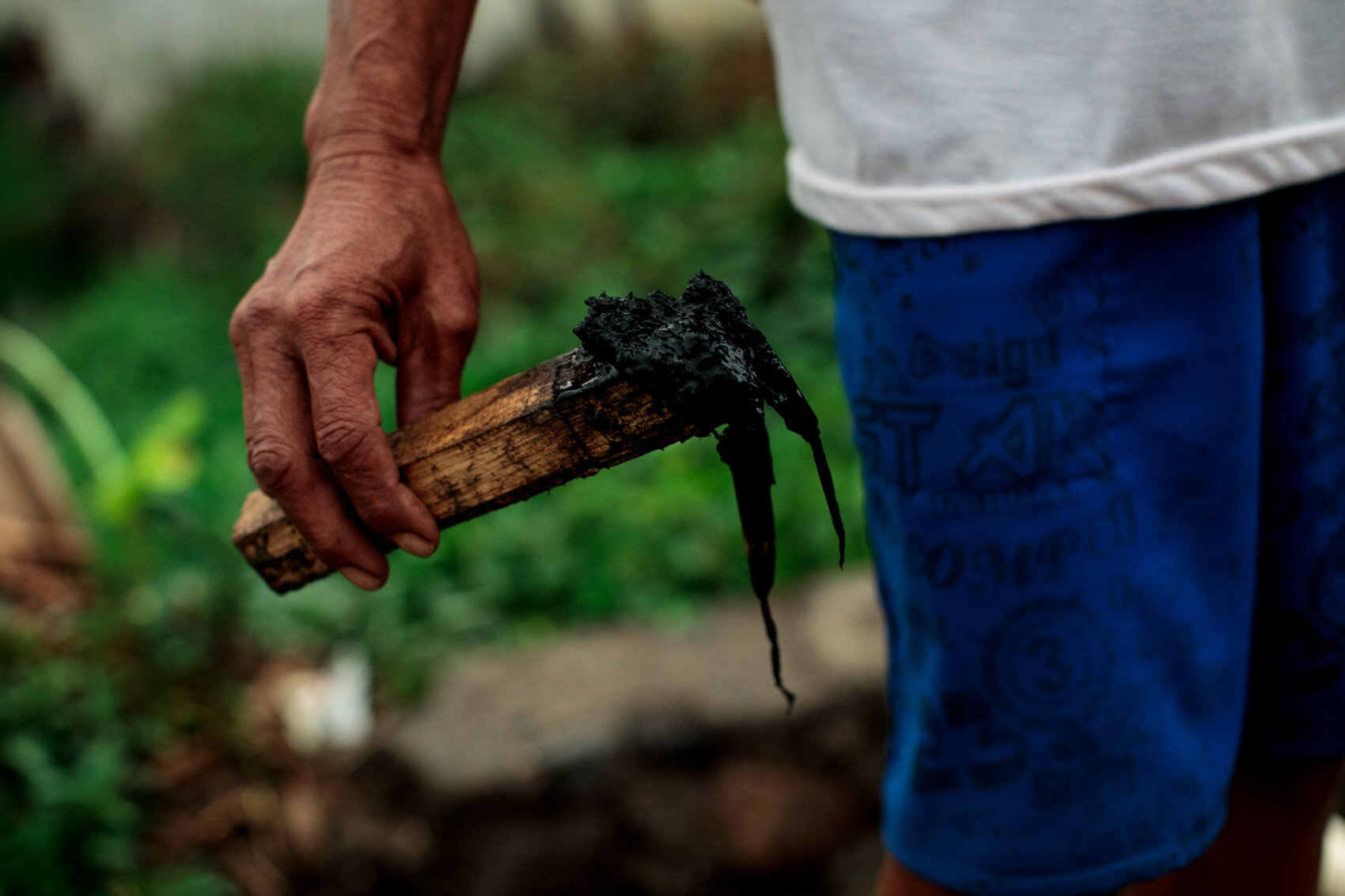  BANDUNG, INDONESIA: Former farmer Ade Traguna, 65, holds a stick covered in the black sludge collected from his rice paddies, on which he can no longer grow crops as result of the toxic water from the Citarum in Jelegong village on November 23, 2019