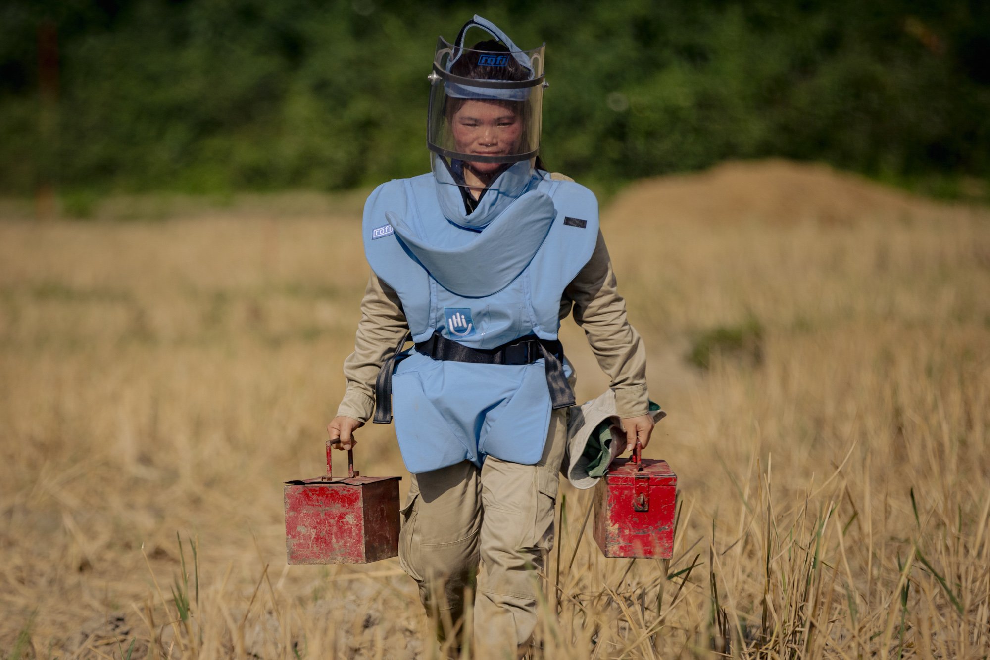  Section Commander Ket, 30, carries detonators before a controlled demolition of a sub-munition found in a rice paddy littered with unexploded ordnance (UXO) near Muang Mai, Laos. 