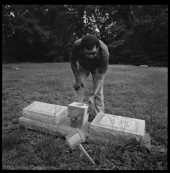 Bud Spires puts his hand on the gravestone of his playing partner Jack Owens during a visit to the grave shortly after the stone was placed. photo by Bill Steber