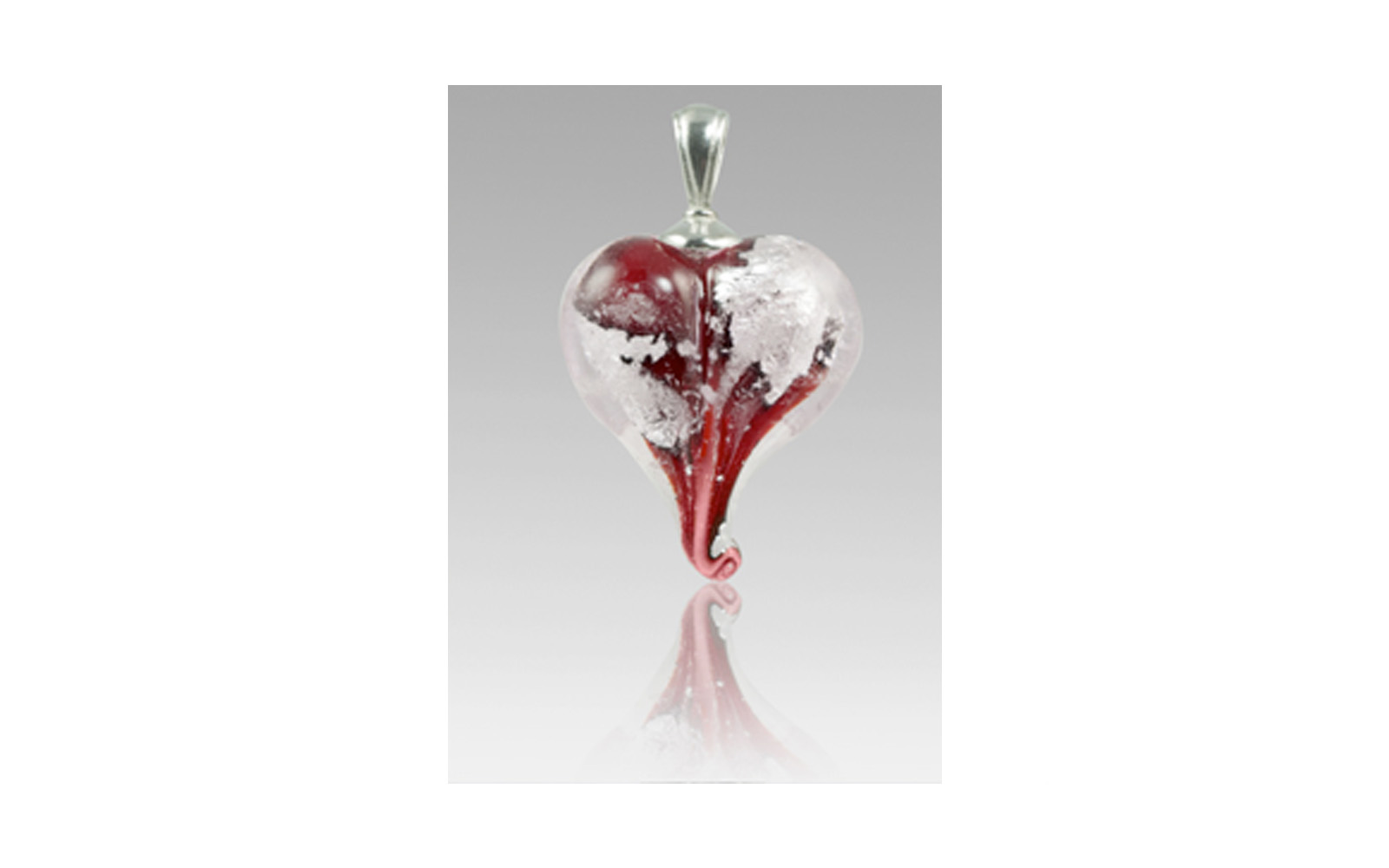 Loving Memory Pendant This Pendant is available in Red, Plum, Pulsar, Green, Blue, Purple, Lavender, and Pink colors. You have a choice of either 14k Gold or Sterling Silver added inside the glass and each piece comes with either a Sterling Silver or a 24k gold, plated bail. It contains your loved one's cremated remains swirling around the center of the heart. Each is approximately ¾” not including the size of the bail and is custom made to order and comes with a 30" sheer ribbon. Sterling Silver (shown): $215 14k Gold: $225