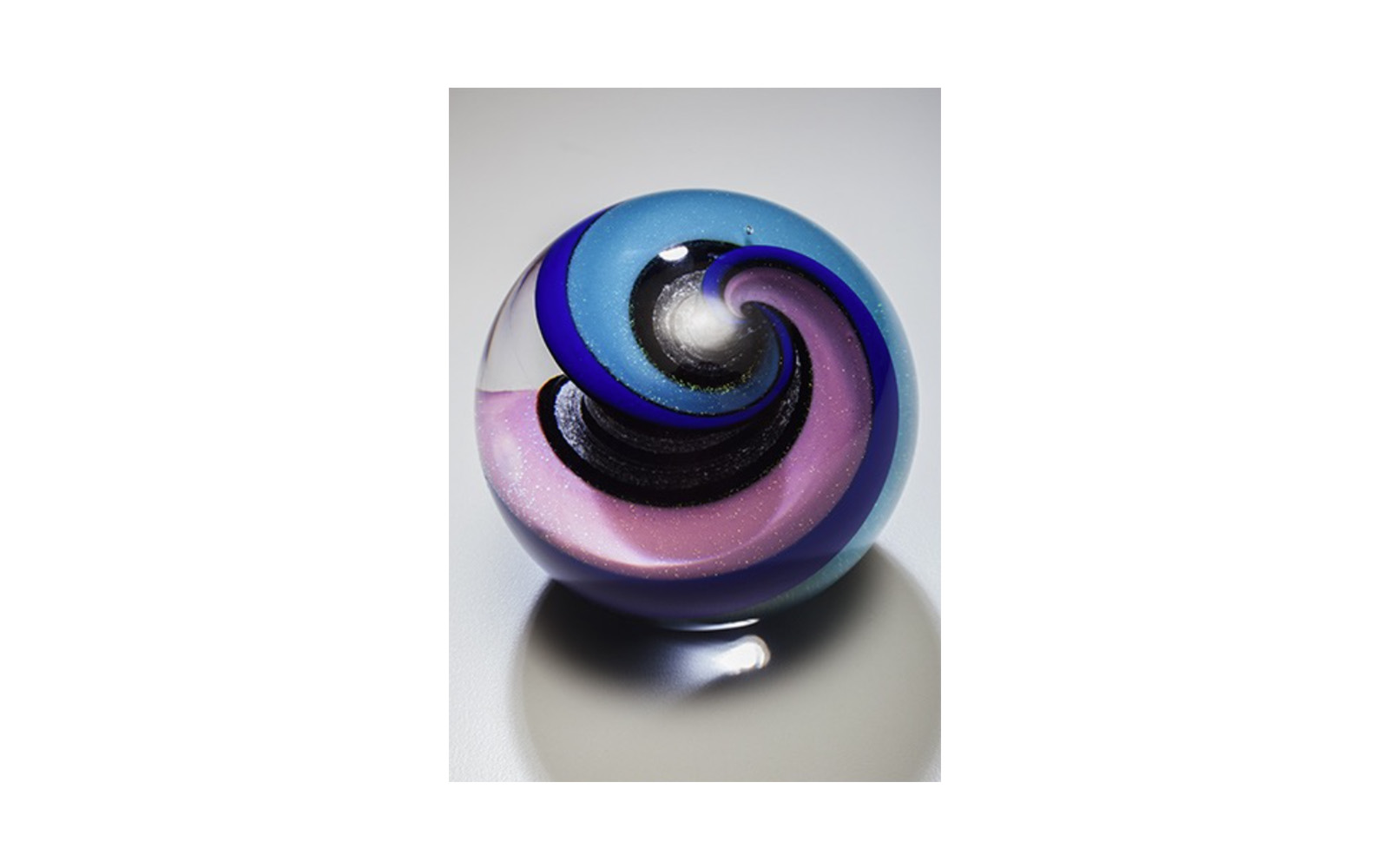Celestial Spring Spiral This perfectly round marble is 3 1/4" in diameter available in three special colors. The iridescent glass twists inside with the cremated remains to give it a Celestial feeling. This piece is truly a marble, so included is a marble ring for standing. $415