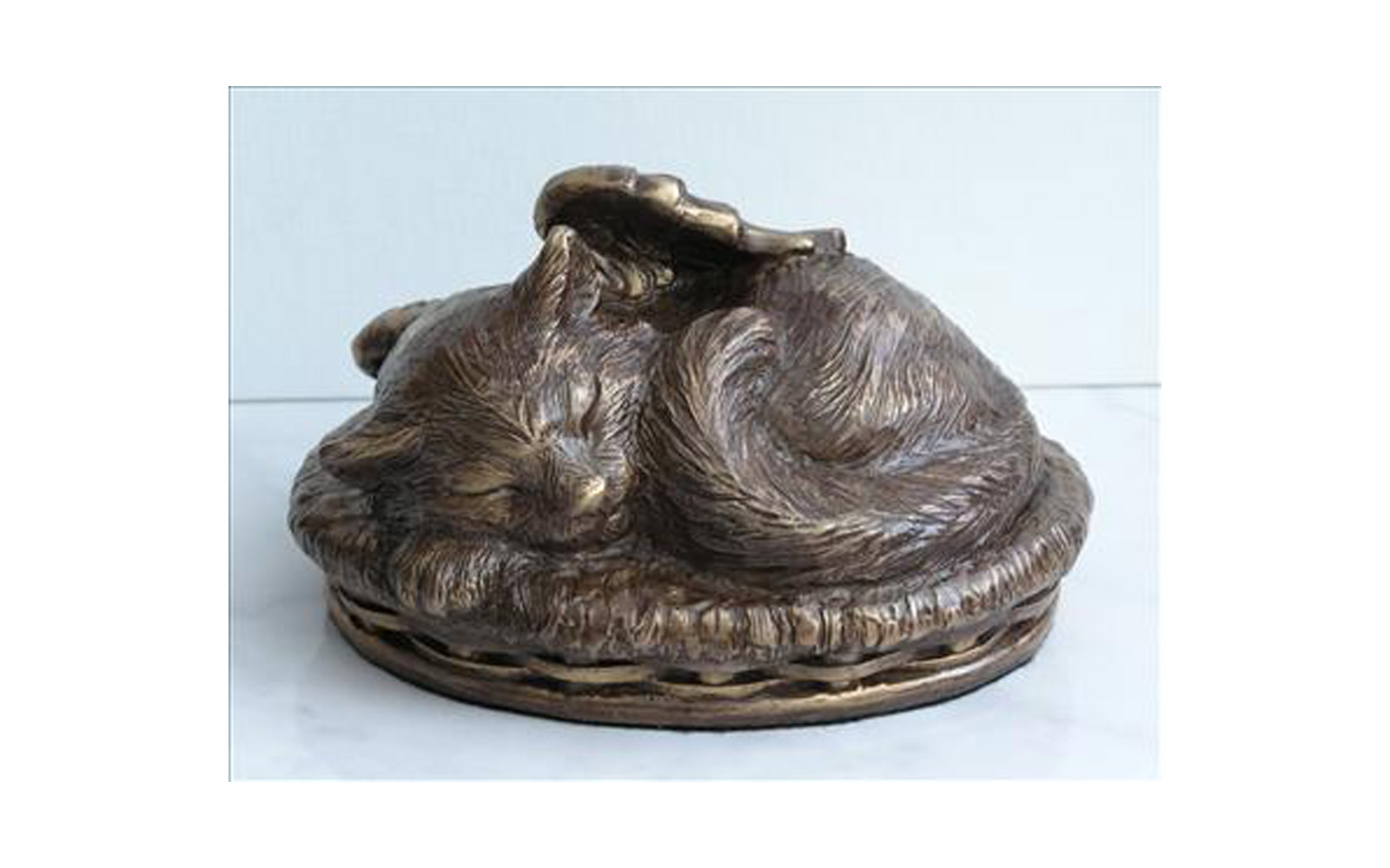 Angel Cat Urn Made of a cold cast bronze (polymer with bronze additive). This piece is available in two versions; with a personalized laser engraved heart shaped name tag on the collar or on the front of the basket an engraved name plate can be attached. Cremated remains are stored through the bottom. Available in Black, White, Bronze, or Verdigris colors. Measures: 7" L x 5" W x 4" H, 30 Cu. Inches, up to 30 lbs. $105 without engraving $125 with engraving
