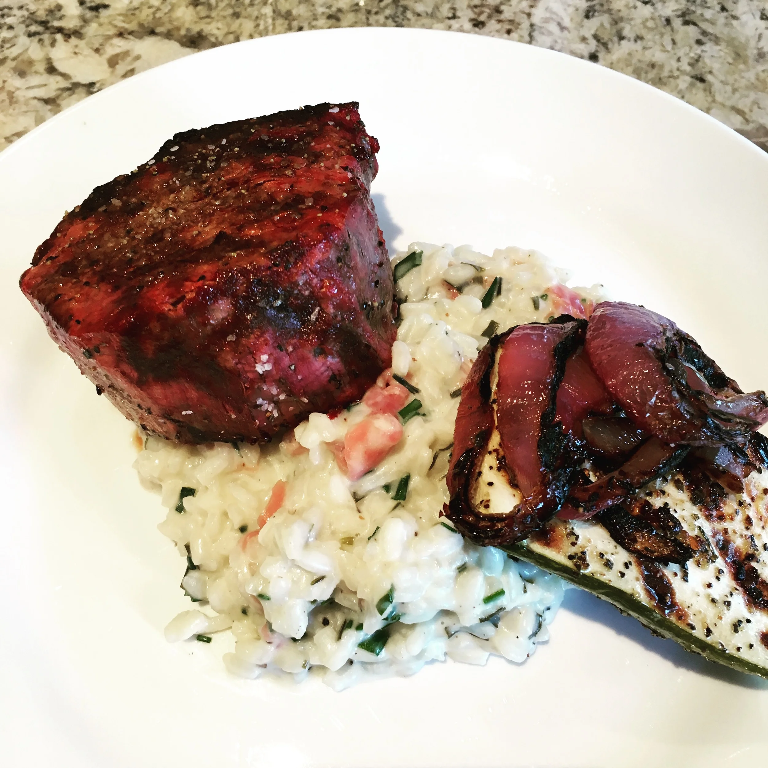 Finished dish of risotto, filet mignon and grilled red onion and squash