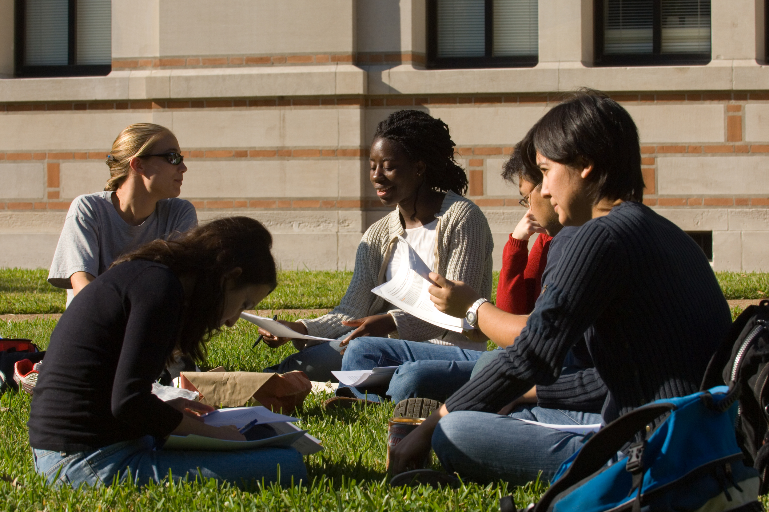 Rice University students sitting in the grass discussing papers.