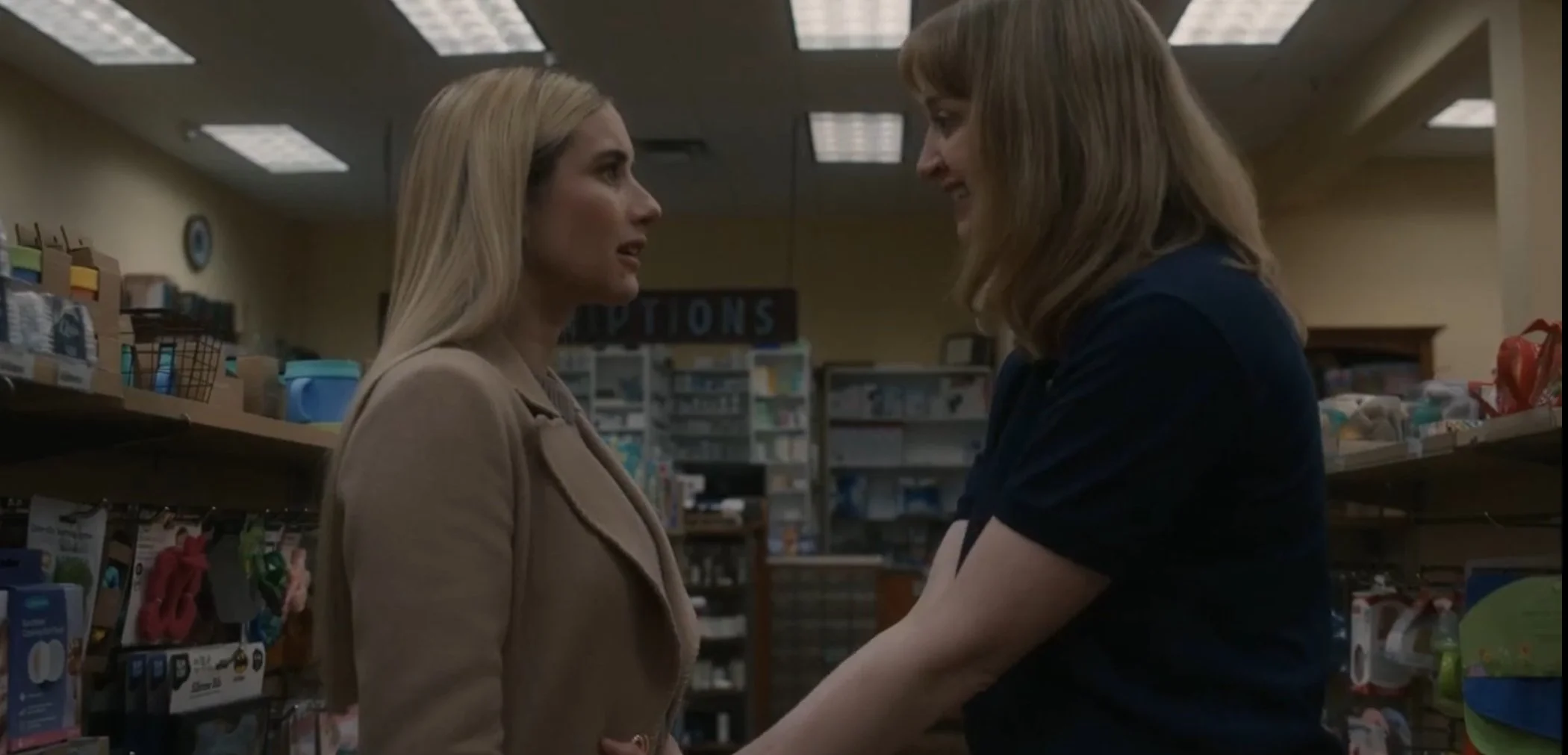 Two women facing each other in a store, smiling and holding hands, with shelves of products in the background.