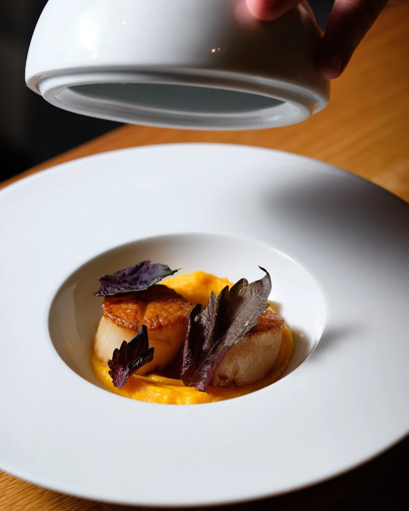 Each element has its moment.

The lid lifts to reveal pan-seared sea scallops with sweet potato, crispy rice, and roasted peppers &mdash; completed with green curry dashi poured tableside.