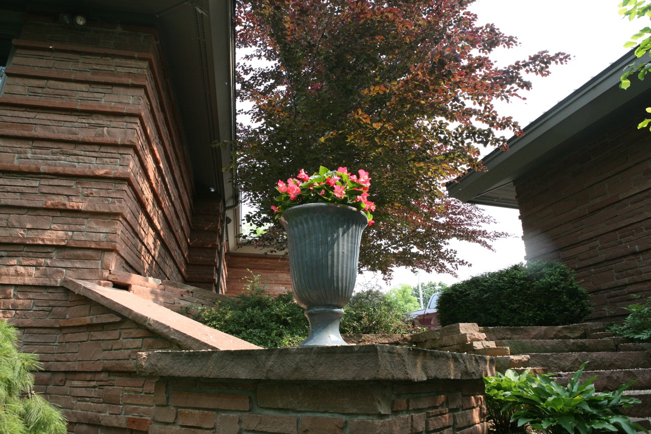    A ceramic urn filled with begonias calls our attention and draws us further into the garden.     