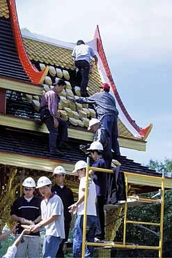 "Some of the university's Thai students help stack roof tiles. Visitors were invited to sign their names on the backs of the tiles that now cover the roof of the pavilion. " Source: U of Wisconsin (Photo: Michael Forster Rothbart ) 