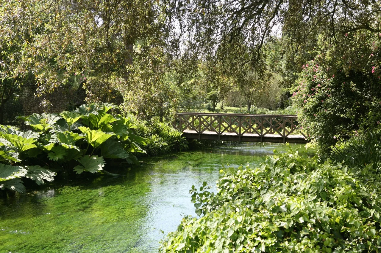 The river Ninfa flows along the southern border of the garden. Bridges connect to the broader preserve land.