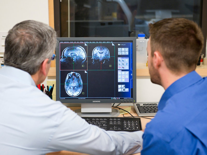 Jeffrey Iliff (right) and Bill Rooney, brain scientists at Oregon Health & Science University, look over an MRI. The school has an especially sensitive MRI unit that should be able to detect precisely when during sleep the brain is being cleansed of toxins. Courtesy of Oregon Health & Science University